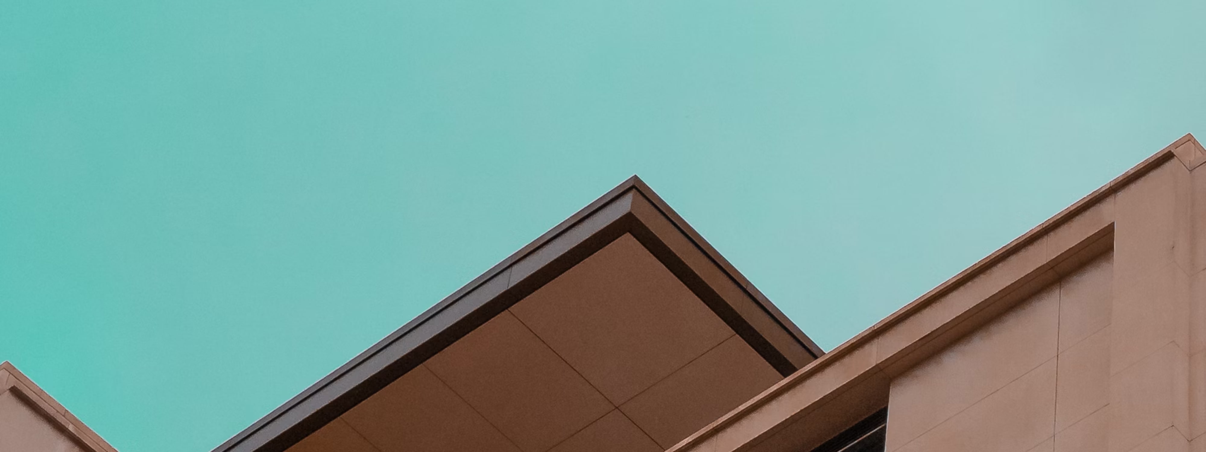 Modern building rooftops against turquoise sky with geometric architectural lines