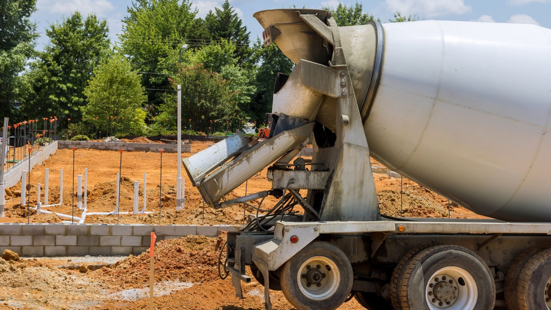 Concrete mixer truck pouring cement at construction site with foundation work