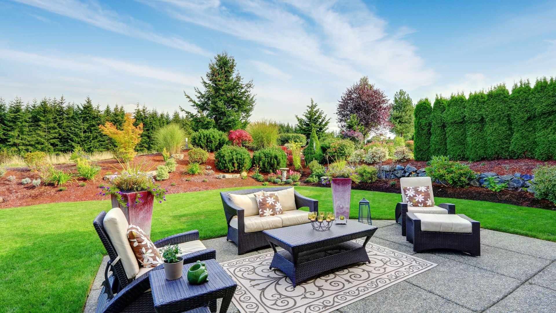 Elegant backyard patio with wicker furniture and lush landscaped garden
