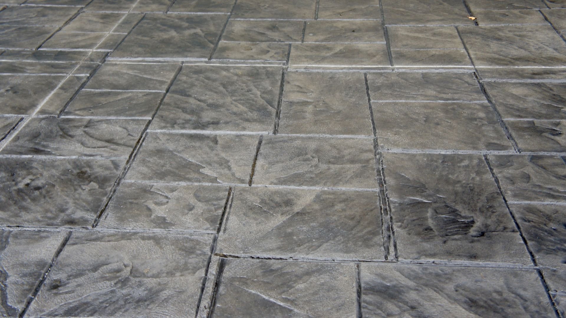 Textured gray concrete patio with stamped stone-like pattern and grout lines