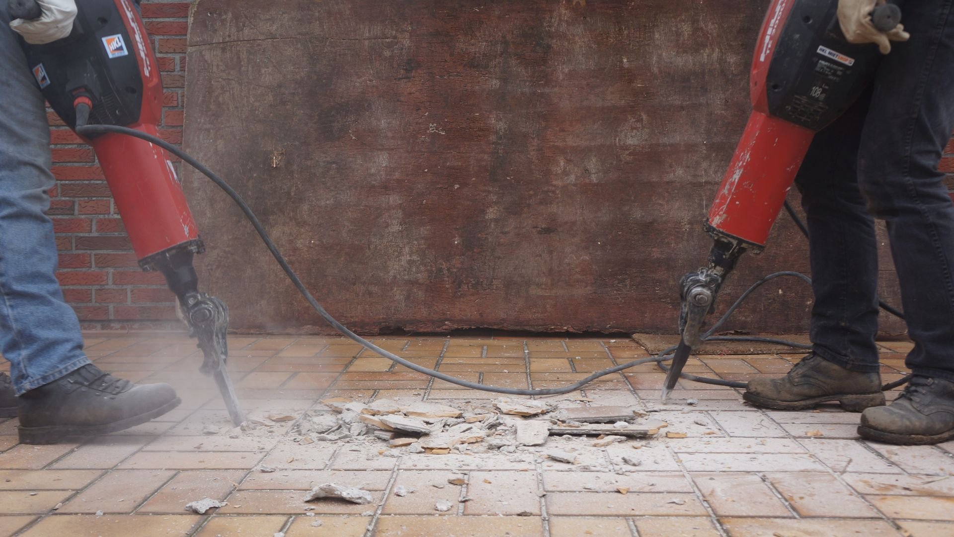 Workers using pneumatic jackhammers to break up ceramic tile floor